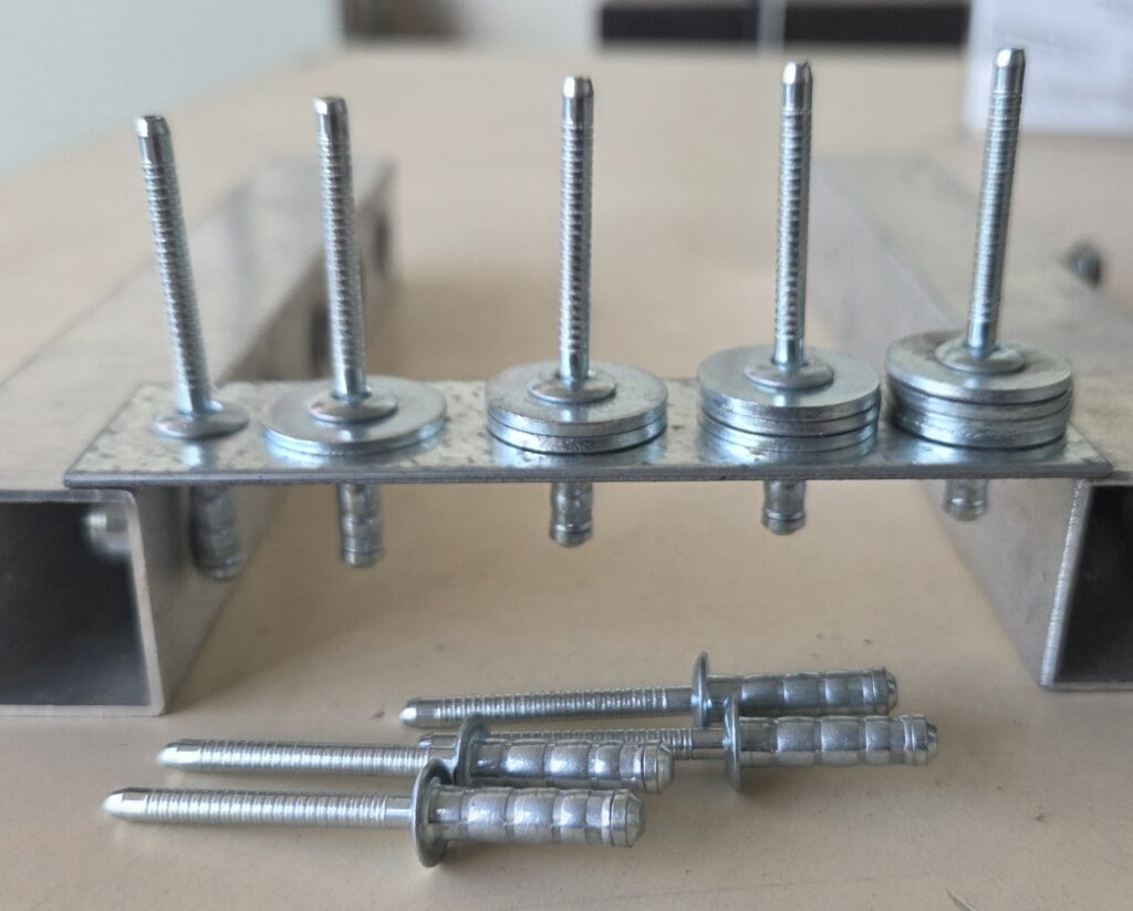 Metal fastening components arranged on a steel support channel before installation.