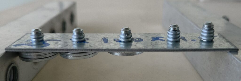 Bottom view of multigrip fasteners installed through a metal sheet showing the formed fastener ends.