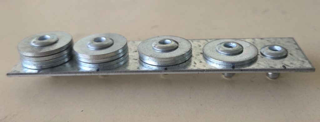 Top view of multigrip fasteners installed through a metal sheet with large washers and fastening heads visible.